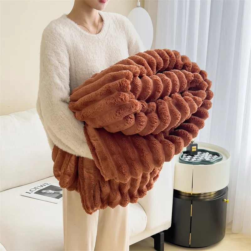 A plush cozy fleece blanket in a rich brown color is draped over a person sitting on a white sofa.