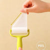 A hand is using a yellow mini portable lint roller to remove lint from fabric.