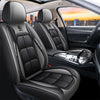 Interior view of a car seat with black leather covers and headrests, showing the seat fabric and console.