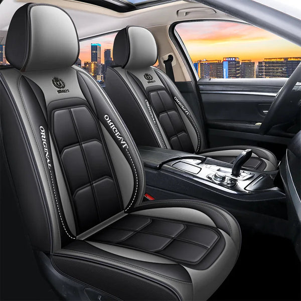 Interior view of a car seat with black leather covers and headrests, showing the seat fabric and console.