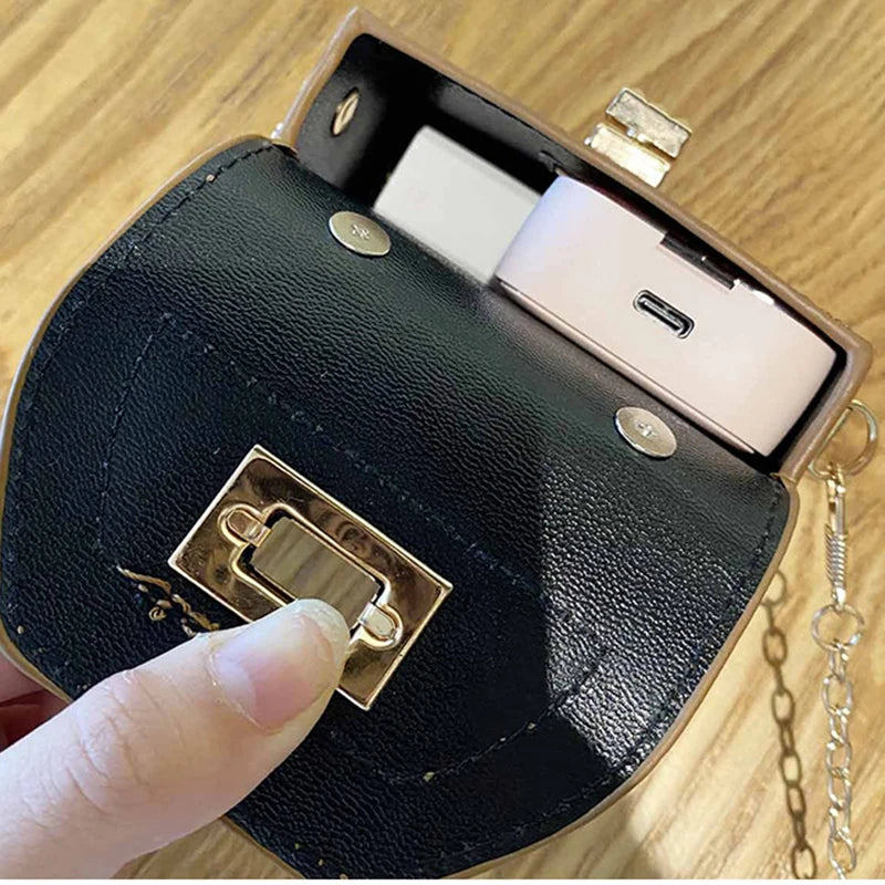 A close-up of a black mini floral textured crossbody tote bag with a gold clasp and a white phone inside.