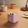 A pink silicone protective case for a Toniebox 2 audio player sits on a wooden desk next to a mug and a small potted plant.