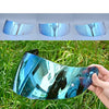 A close-up view of a motorcycle helmet visor lens shield showing blue and purple reflections in natural sunlight.