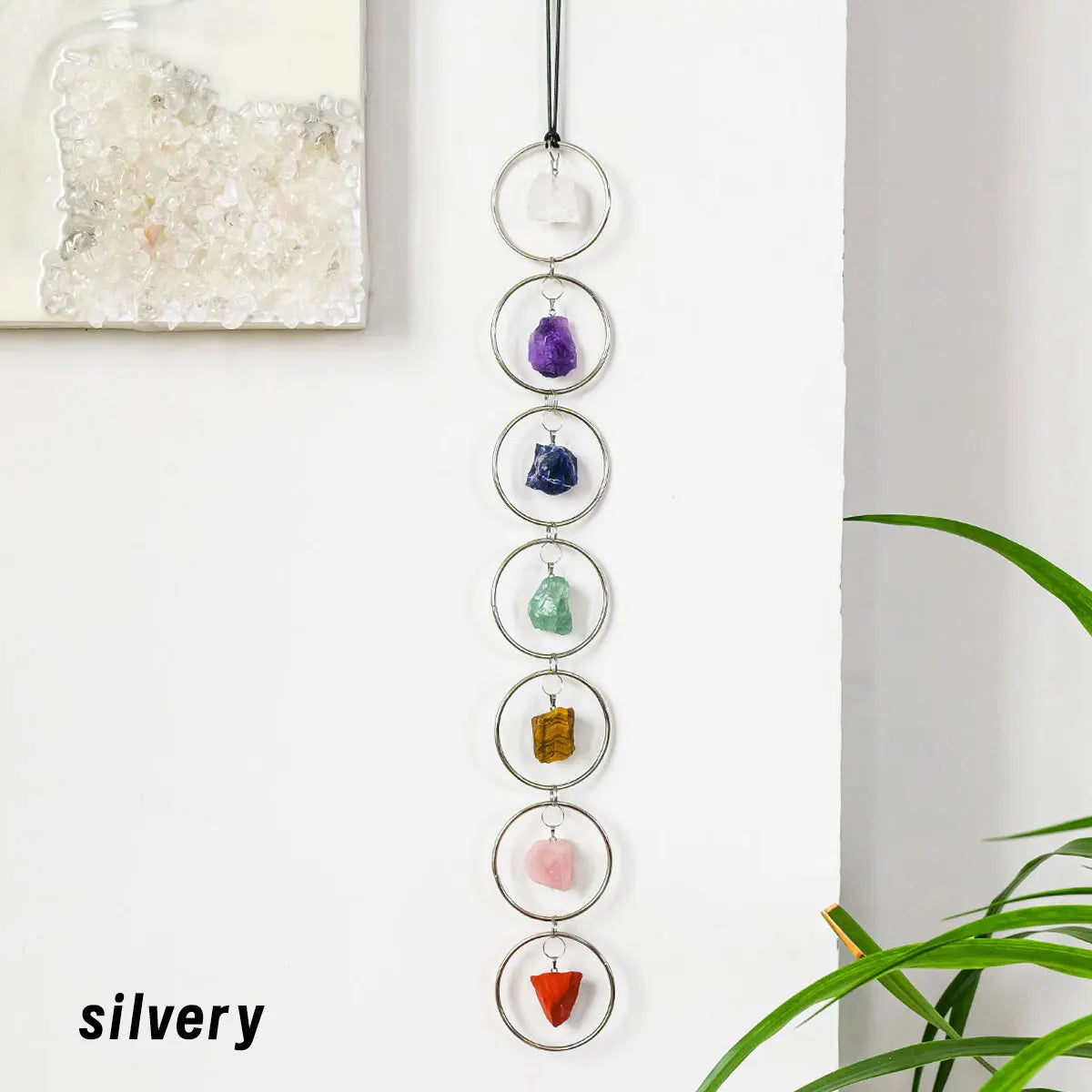 A vertical display of seven polished crystals hanging on a silver chain, representing the seven chakras.