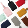 A collection of various colored PU leather luggage tags, including pink, black, red, yellow, and gray.