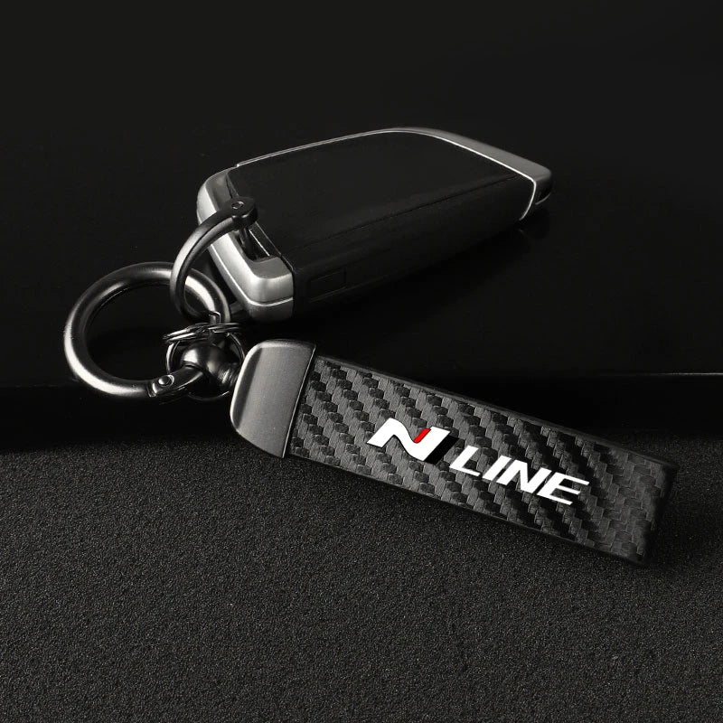 A black keychain featuring a carbon fiber style leather strap with the N LINE logo and a metal swivel buckle.