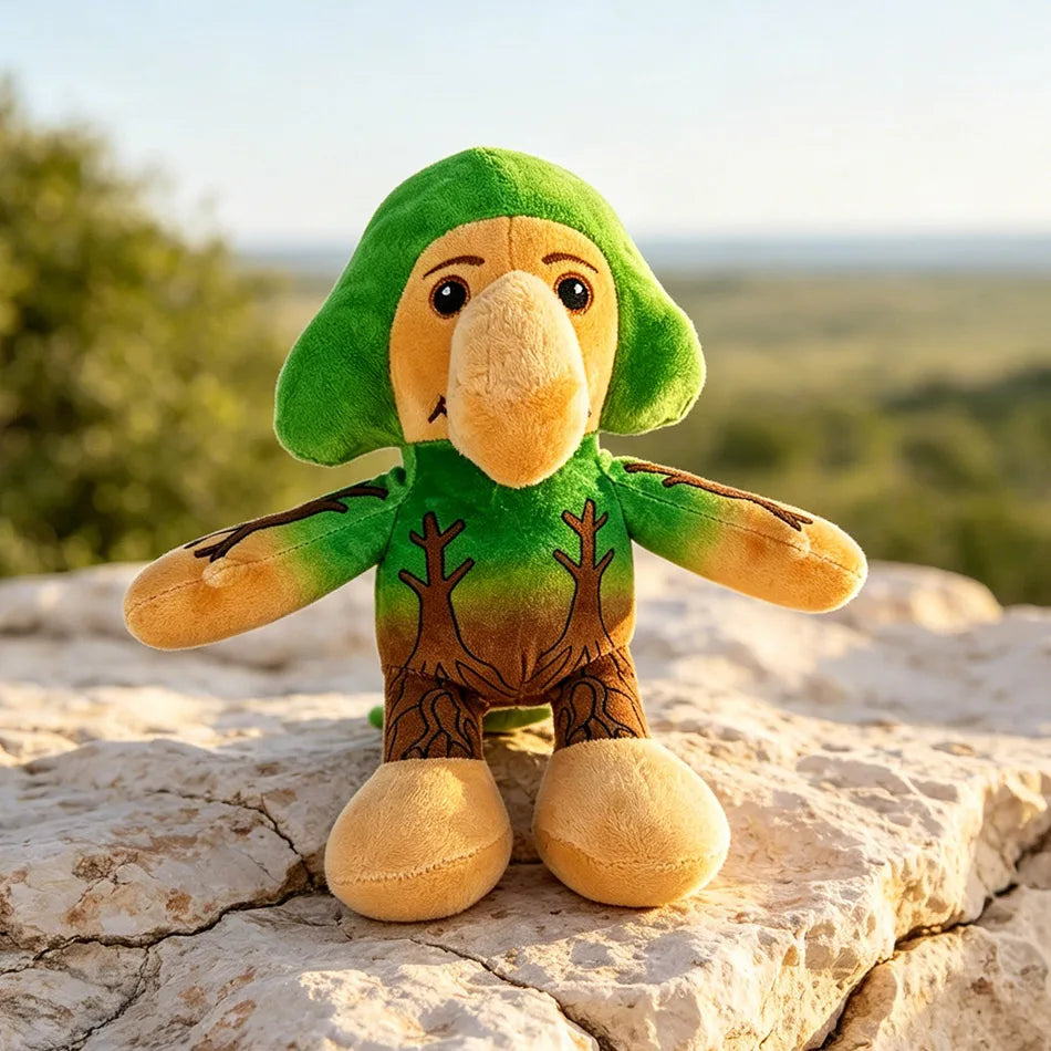 A green and tan shark plush toy sitting on a light-colored rock outdoors.
