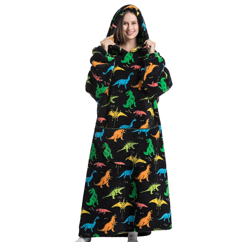 A woman wearing an oversized black hoodie blanket featuring a colorful dinosaur print.
