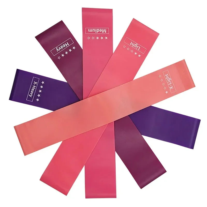 A collection of portable resistance bands in various colors including purple, pink, and red, labeled Heavy, Medium, and Light