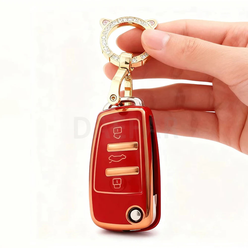 A hand holds a red protective TPU key fob cover with a gold-colored ring and clasp.