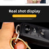 A hand holds a gold brass keychain with a locking carabiner clip.