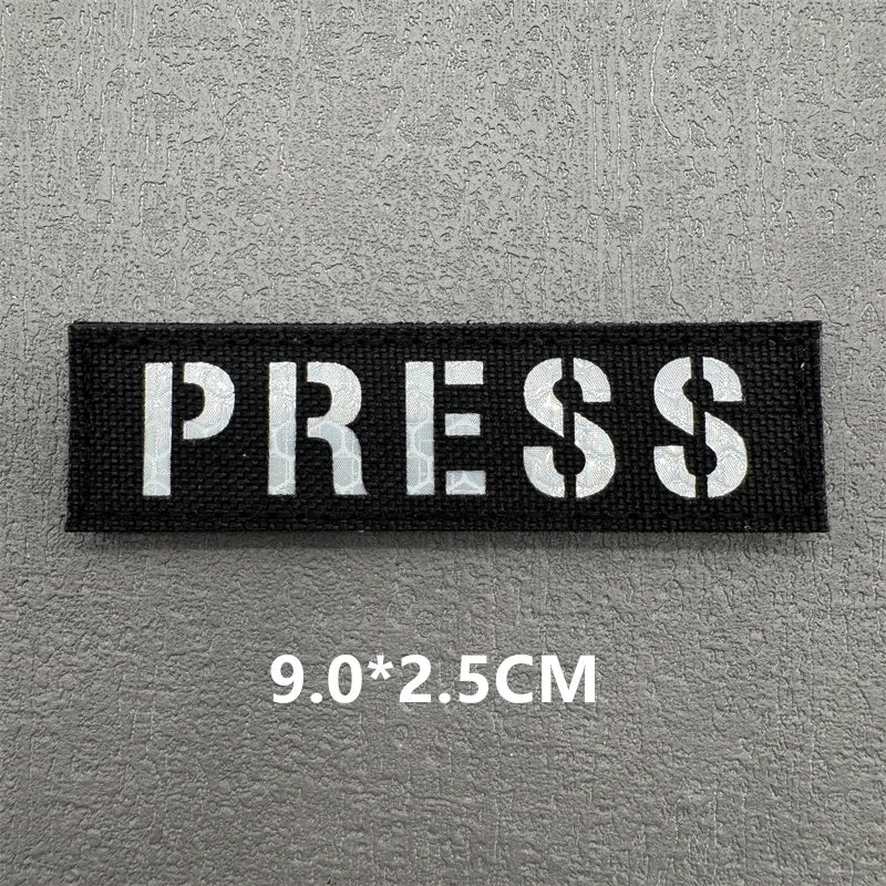 Black rectangular press patch with white text and dimensions 9.0x2.5cm