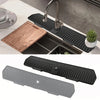 A black silicone faucet mat with a self-draining tray is shown installed in a kitchen sink.
