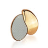 A gold-toned hair remover with a teardrop shape and a textured silver surface.