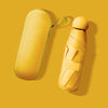 A yellow compact five-fold umbrella with a green strap is shown against a mustard yellow background.