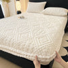 A white warm plush mattress cover with an elastic edge is shown on a black bed frame.