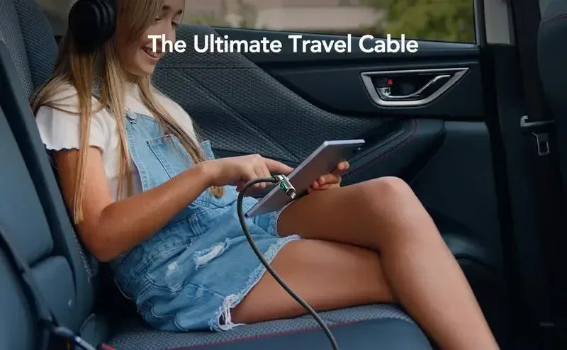 A young woman is using a multi USB-C cable in the interior of a car, likely for charging or data sync.