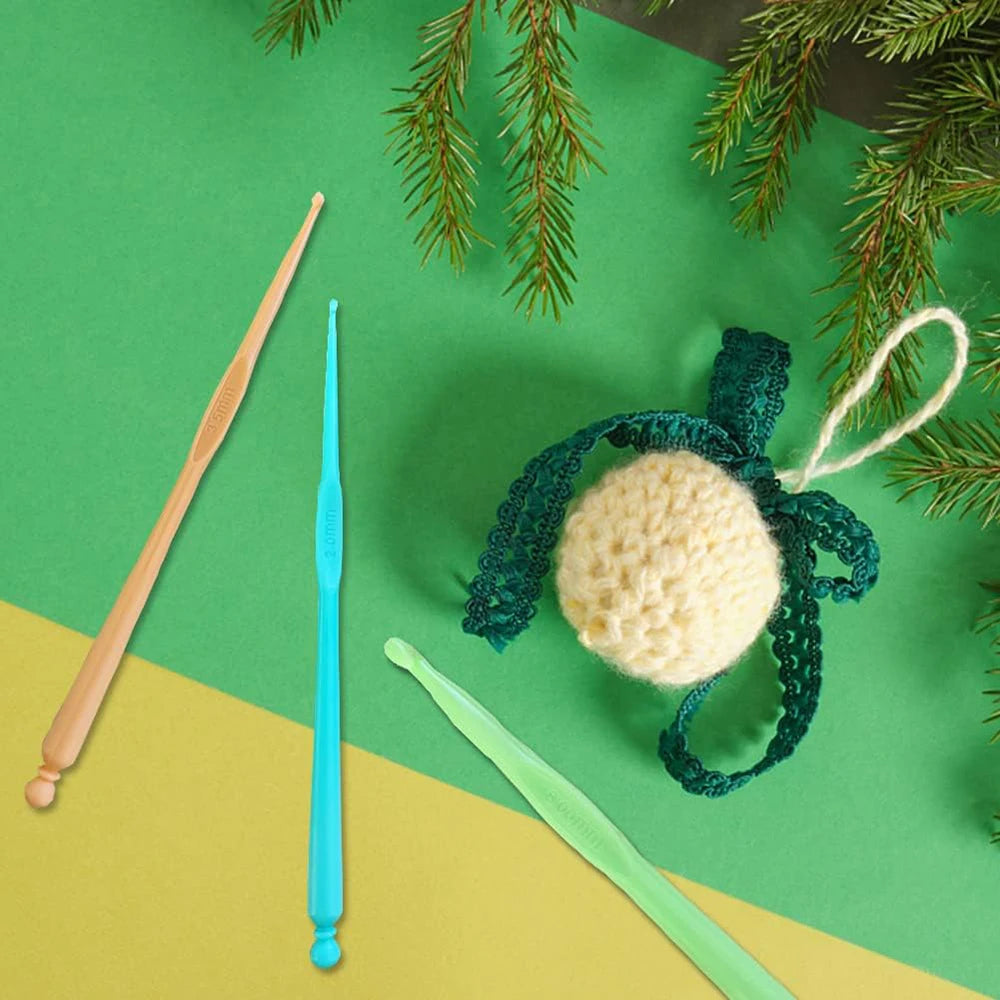 A set of colorful plastic crochet hooks, including a long wooden hook and a green crocheted hook with a yellow pom-pom.