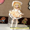 A blonde BJD doll wearing a white and peach maid dress outfit with a wide brim hat and brown ribbon details.