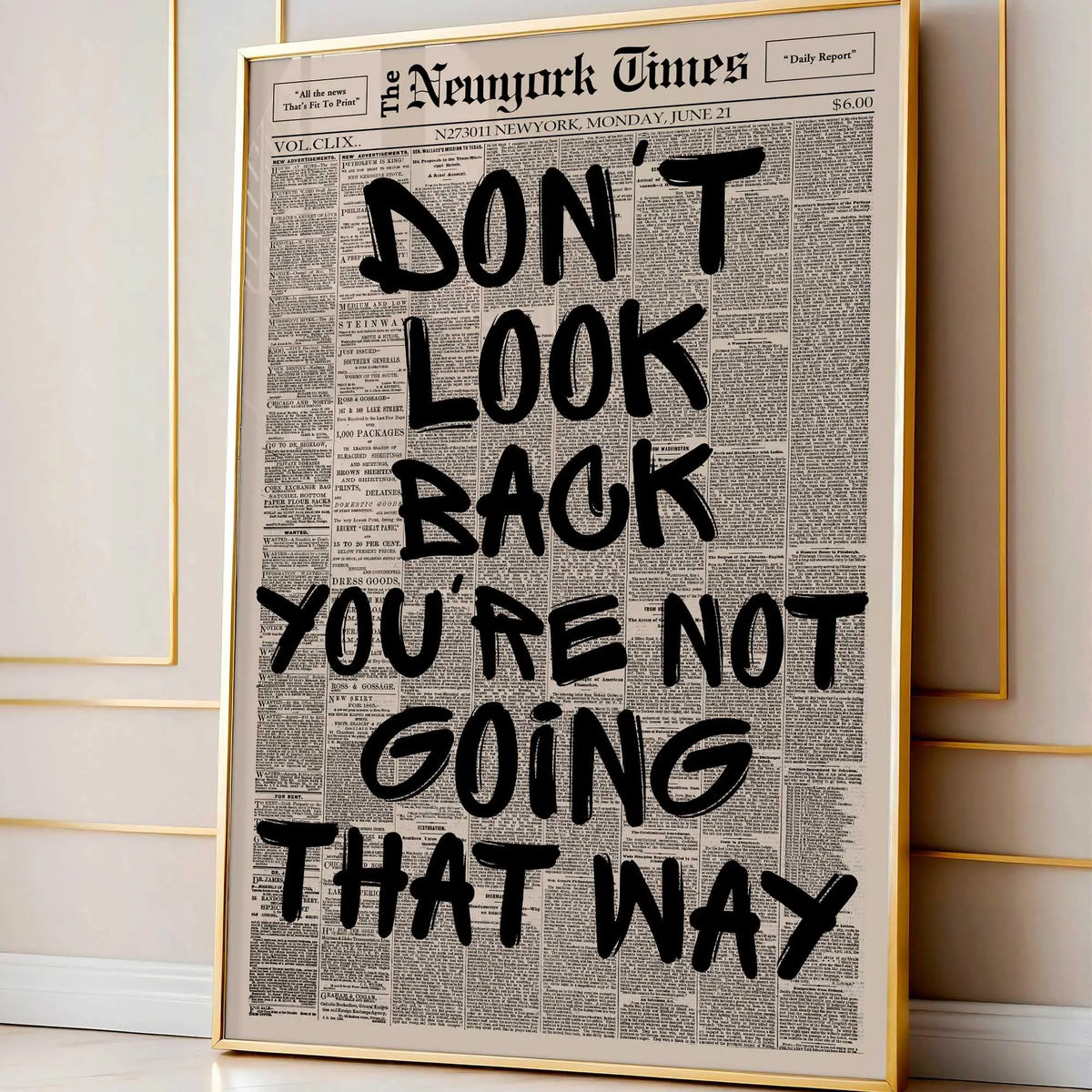 Framed canvas wall art featuring a black and white newspaper-style quote that reads Don't look back you're not going that way