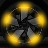 Close-up of a reflective wheel rim strip with a multi-spoke design glowing yellow against a dark background.