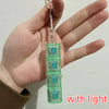 A hand holds a clear green LED mechanical keychain fidget toy with custom keycaps.