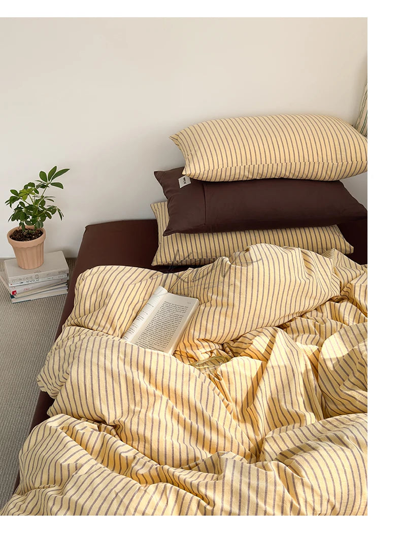 A set of minimalist striped 100% cotton duvet covers in beige and brown tones displayed on a bed.