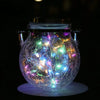 A crackle glass solar lantern glowing with warm ambient light against a dark background.