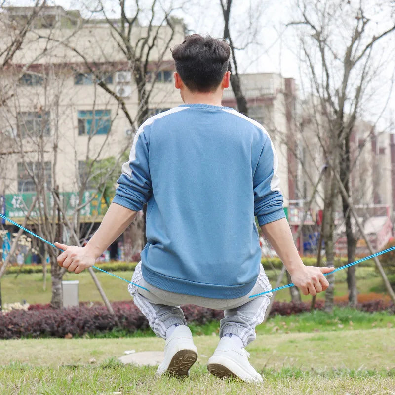 A man is using a portable windproof clothesline to dry clothes outdoors in a grassy area.