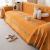 An orange bohemian jacquard sofa cover with patterned fabric and a white mug resting on the surface.