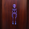 A purple, poseable luminous skull sculpture mounted on a wooden surface.