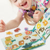 A child is interacting with a Montessori quiet book featuring colorful illustrations and words.