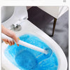 A hand is using a white toilet brush to clean the inside of a white toilet bowl, creating blue foam.
