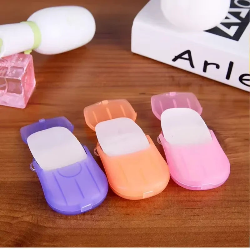 A collection of colorful portable disposable soap tablets in various shades of pink, purple, and orange are displayed on a wo