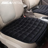 A black quilted car seat cover with anti-slip backing is shown in a light beige vehicle interior.