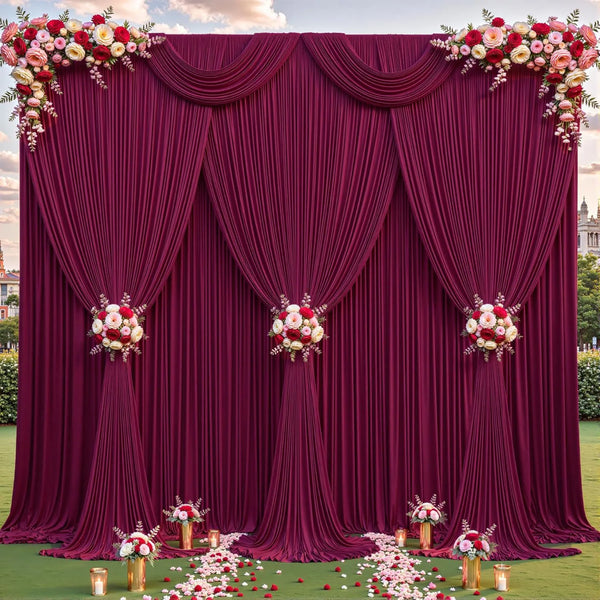 Cortina de tela magenta profunda decorada con toques florales y pliegues sobre un césped verde.