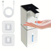 A white touchless automatic soap dispenser with a pump mechanism and a cord, shown next to a hand.