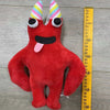 A red plush toy resembling a bird with large eyes and a pink tongue is shown next to a yellow ruler.
