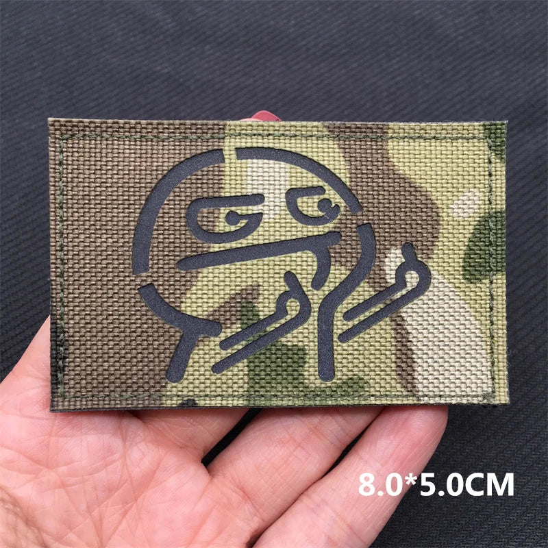 A close-up of a camouflage tactical patch featuring a stylized national flag design on a dark fabric.