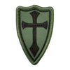 A dark olive green shield-shaped embroidered patch featuring a black cross design.