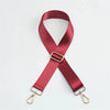 A maroon nylon bag strap with a gold buckle shown in an 'X' shape.