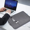 A person is using a laptop and holding a gray waterproof laptop sleeve with a handle on a white desk.