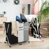 A foldable laundry basket with handles and sorting compartments in black, white, and gray is shown indoors.