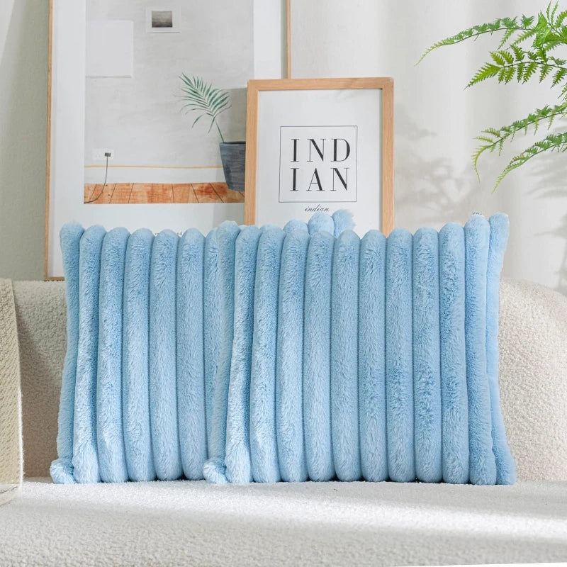 Light blue plush faux fur cushion cover with vertical stripes displayed on a sofa.