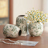 Handgemachte Keramikvase mit weiß-grünem Blumenmuster auf Holzoberfläche