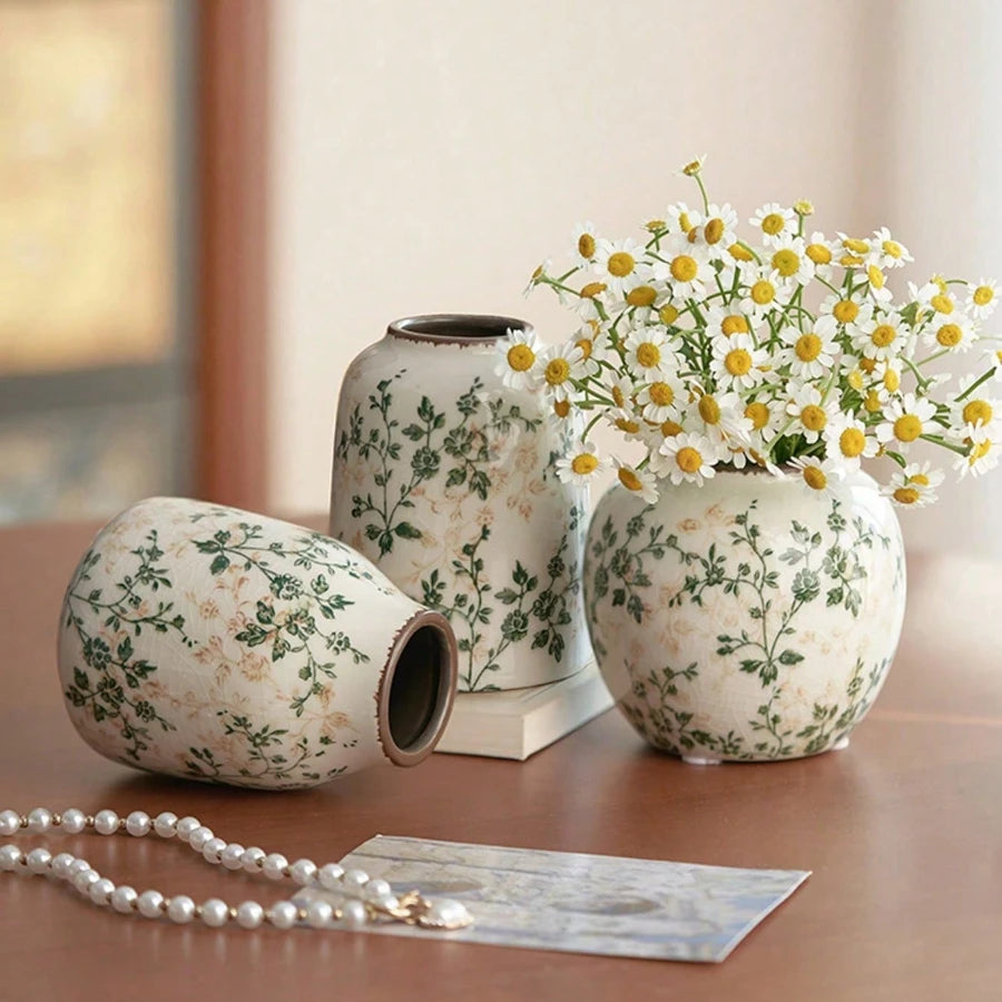 Handgemachte Keramikvase mit weiß-grünem Blumenmuster auf Holzoberfläche