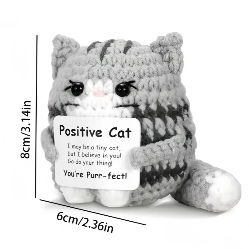 A handmade crochet cat doll with a striped gray and white body and a positive message card.