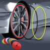 A close-up of a car wheel rim with protective trim, showing a black edge guard and a yellow ring, next to a roll of colored t