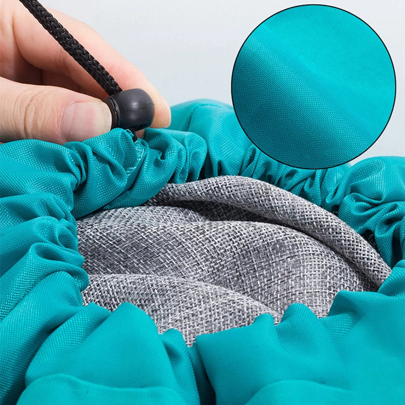 A hand is drawing a drawstring closure on a teal laundry bag, revealing a gray mesh interior.