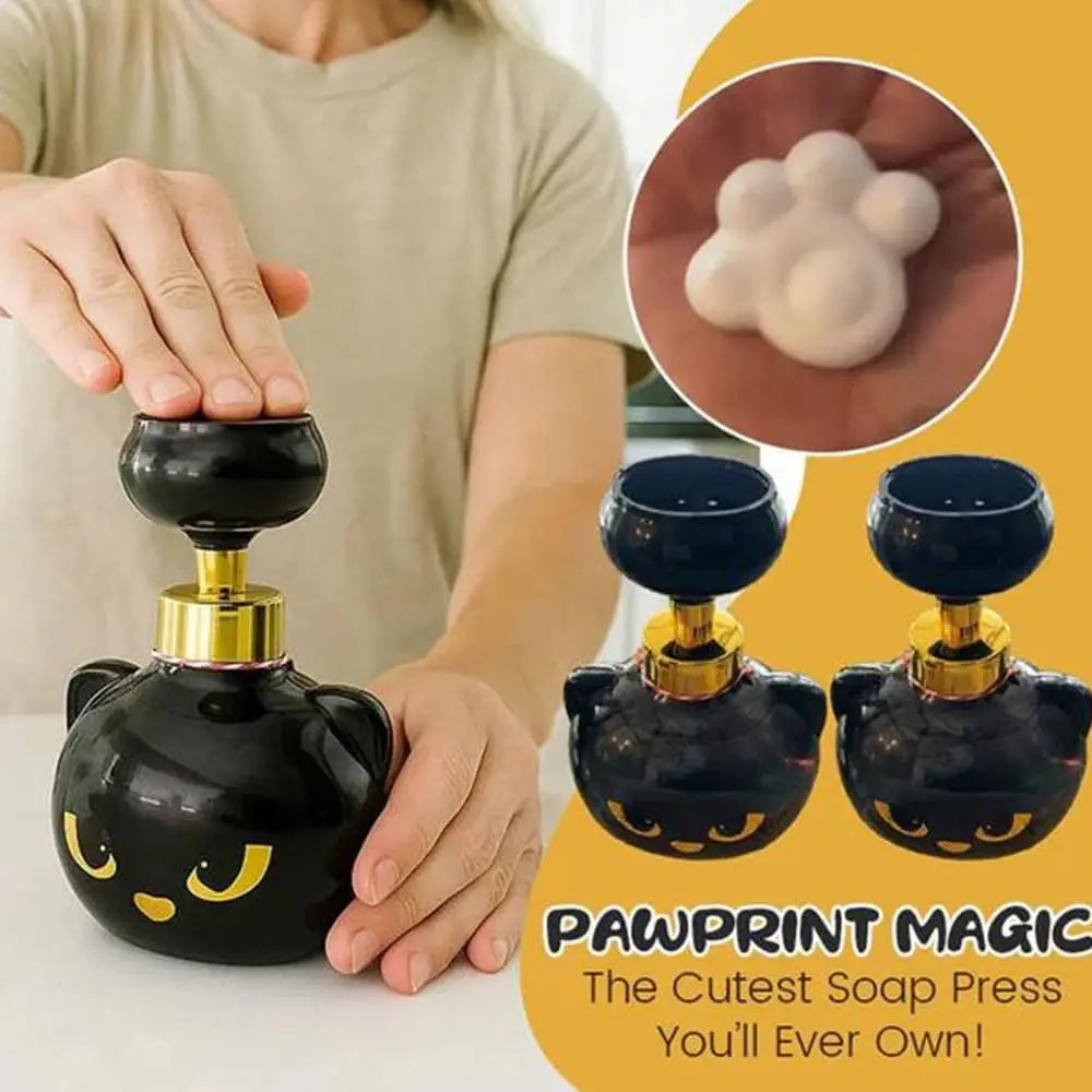 A black cat paw shaped soap press dispenser with a gold top is shown next to a hand and a close-up of foam soap.